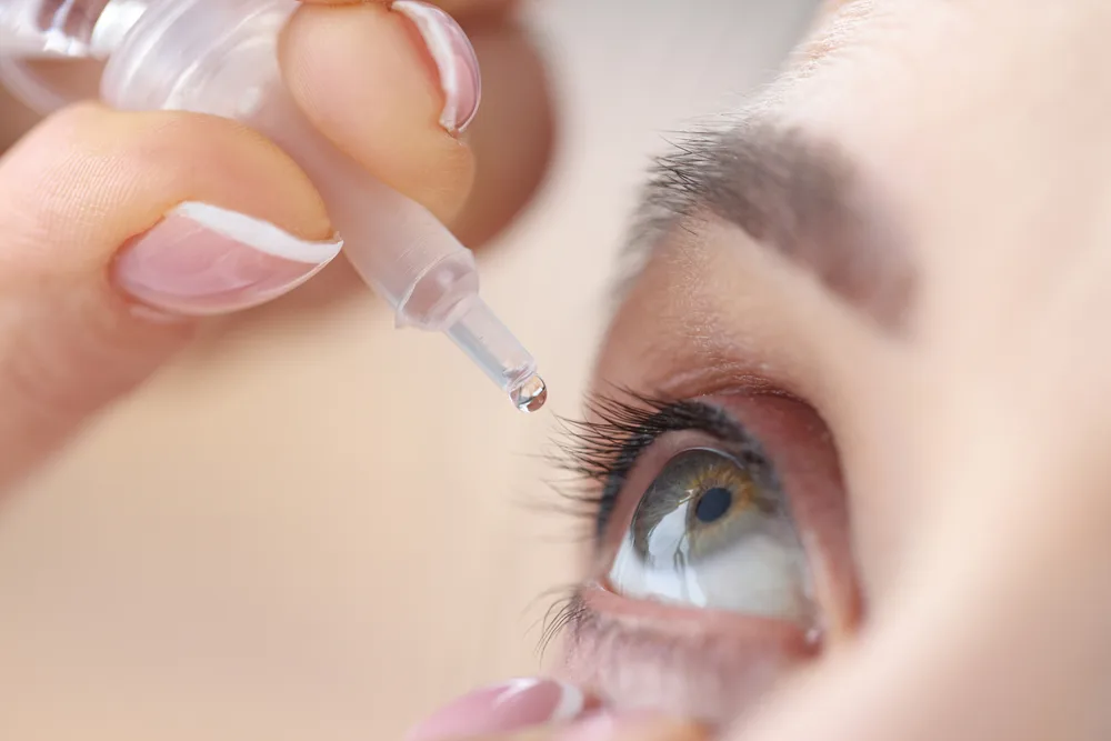 Person putting eye drops into their eye
