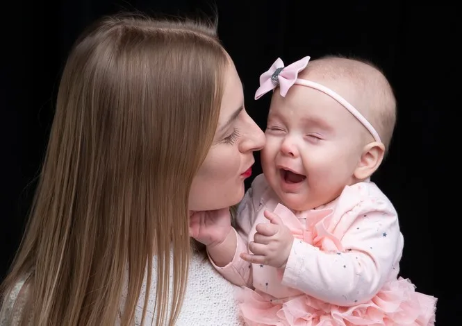 Mom holds her little girl in her arms.