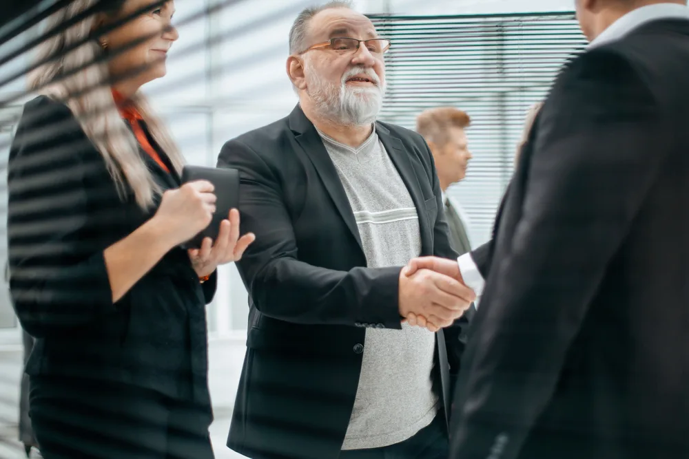 Person wearing eyeglasses shakes hands with an individual