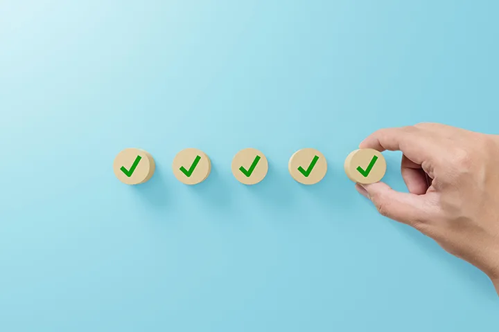 Check mark on wooden blocks on light blue background.