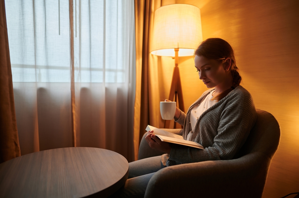 Person reading a book by lamplight