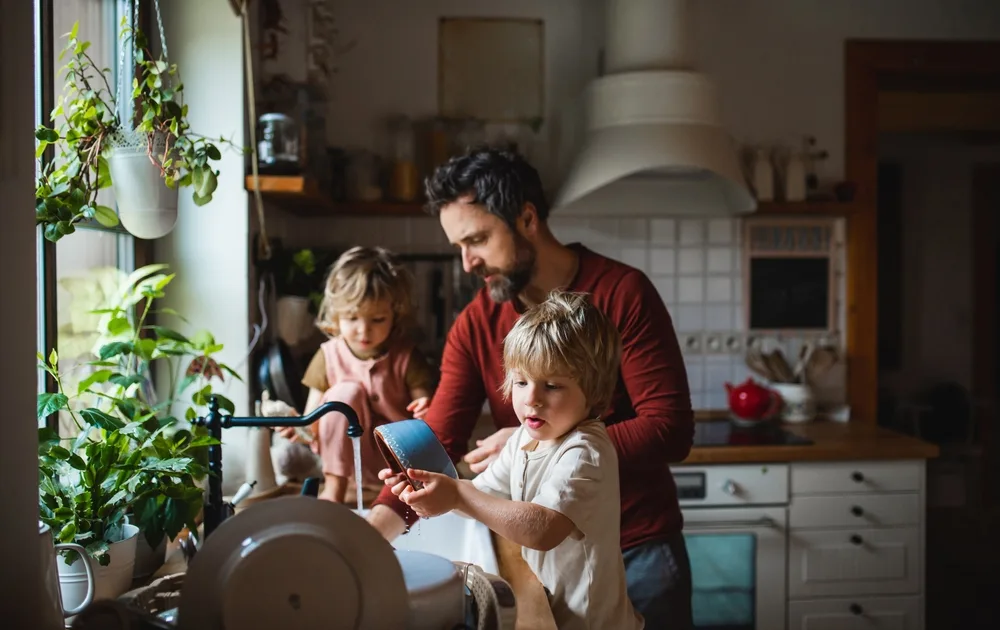 Person washes dishes alongside two children