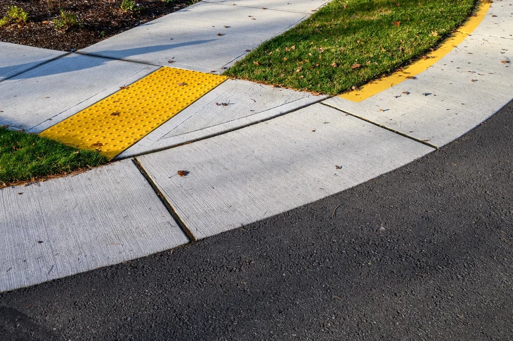 Closeup of disabled sidewalk entry on a cold sunny day, yellow markings