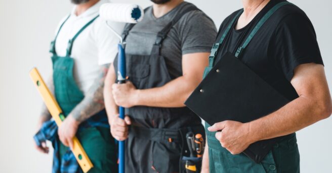 three people wear aprons and hold home repair gear