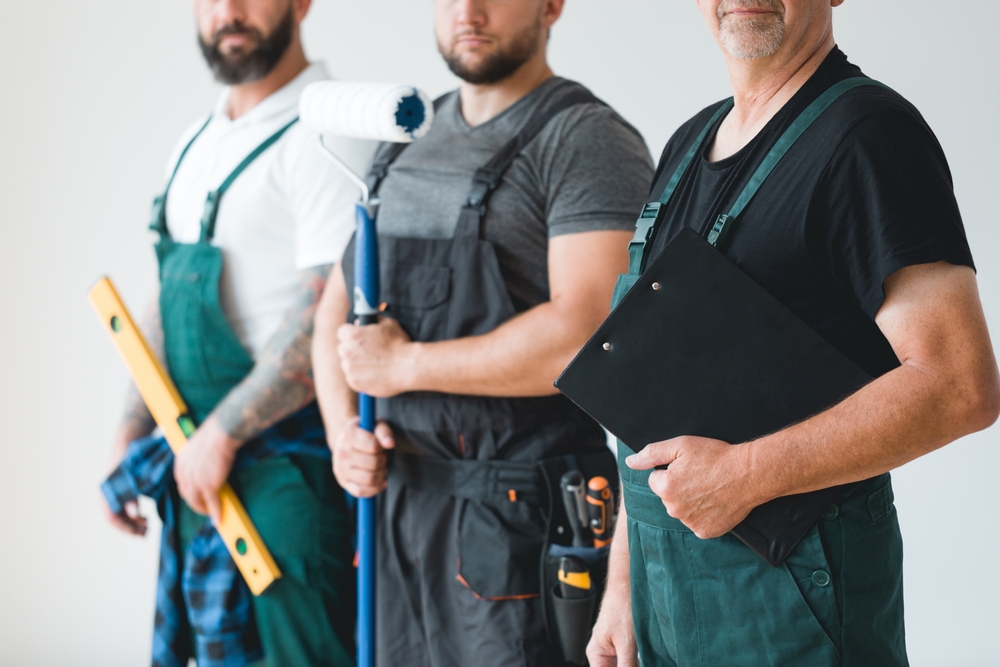 three people wear aprons and hold home repair gear