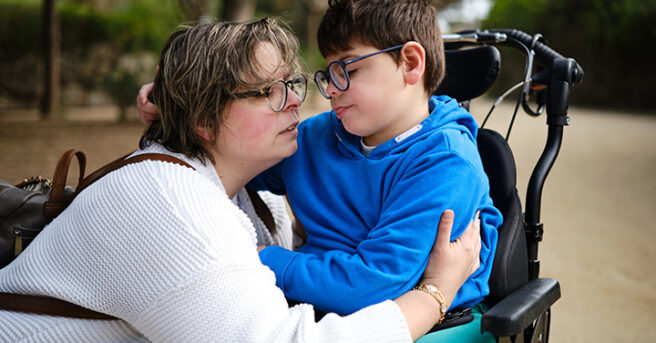 boy in a wheelchair and his mother enjoying a day together outdoors in a park