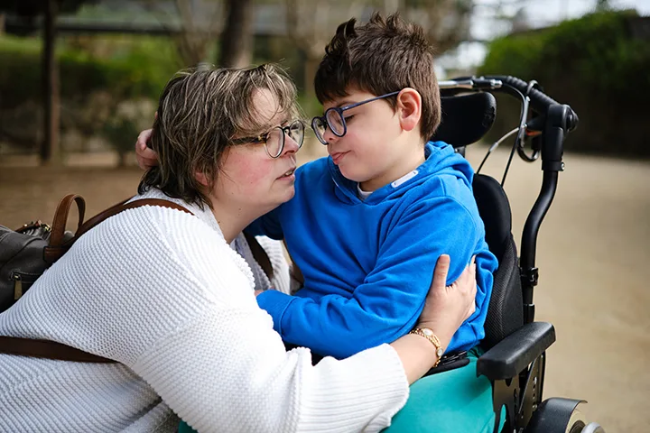 boy in a wheelchair and his mother enjoying a day together outdoors in a park