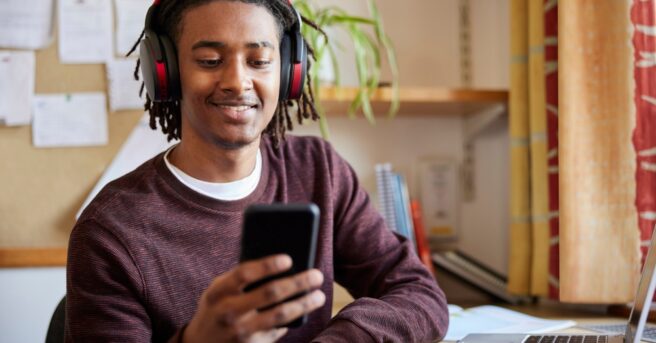 Student in dorm using headphones and a smartphone