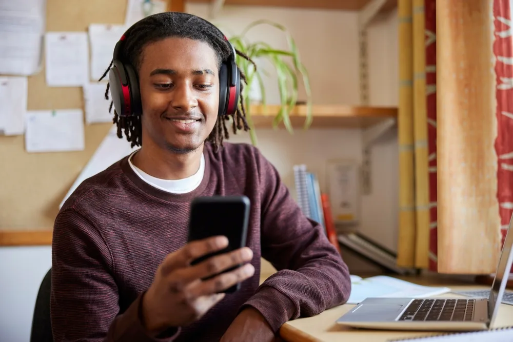 Student in dorm using headphones and a smartphone