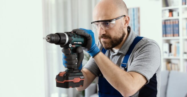 Person wearing safety goggles and drilling a hole into a wall