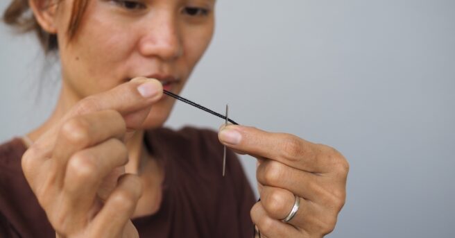 Person holds a threaded needle