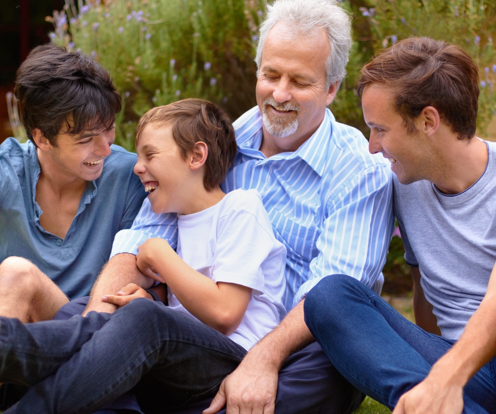 Multigenerational group of men and boys smiling and laughing outdoors.