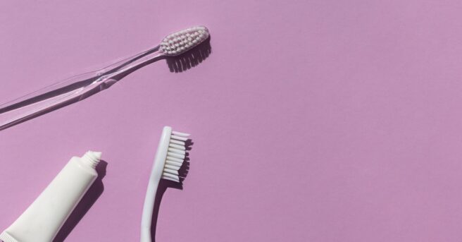 Toothbrushes and toothpaste against a solid background