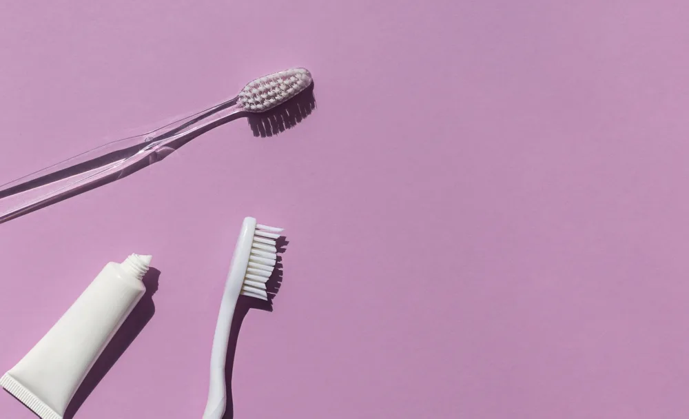 Toothbrushes and toothpaste against a solid background