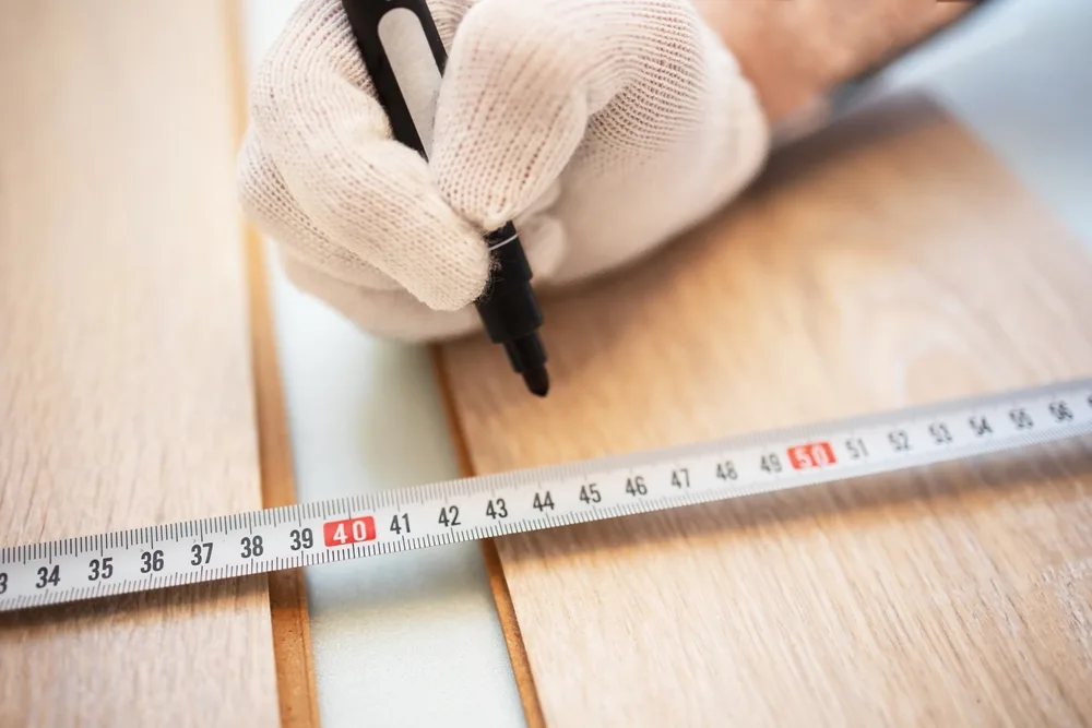 Person using a permanent marker to mark the measurement of wood