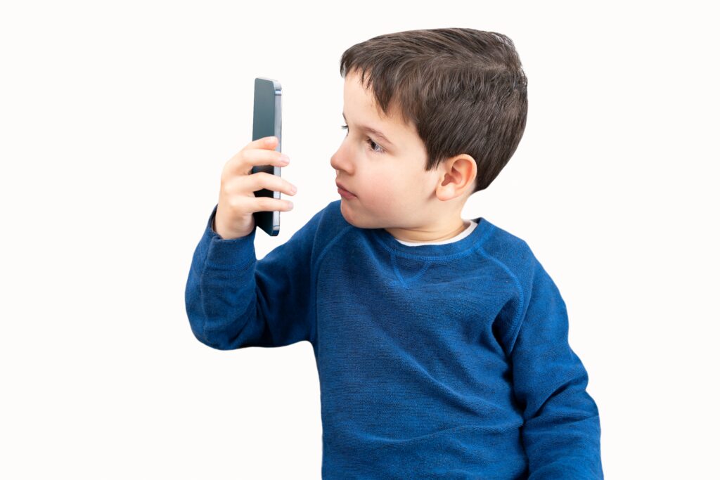 Boy holding a phone up close to his face, trying to read the screen.