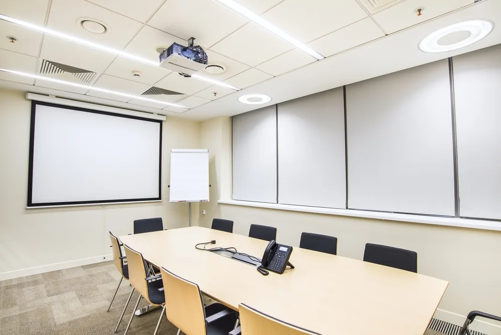 Small empty conference room with TV projector, conference table and chairs.