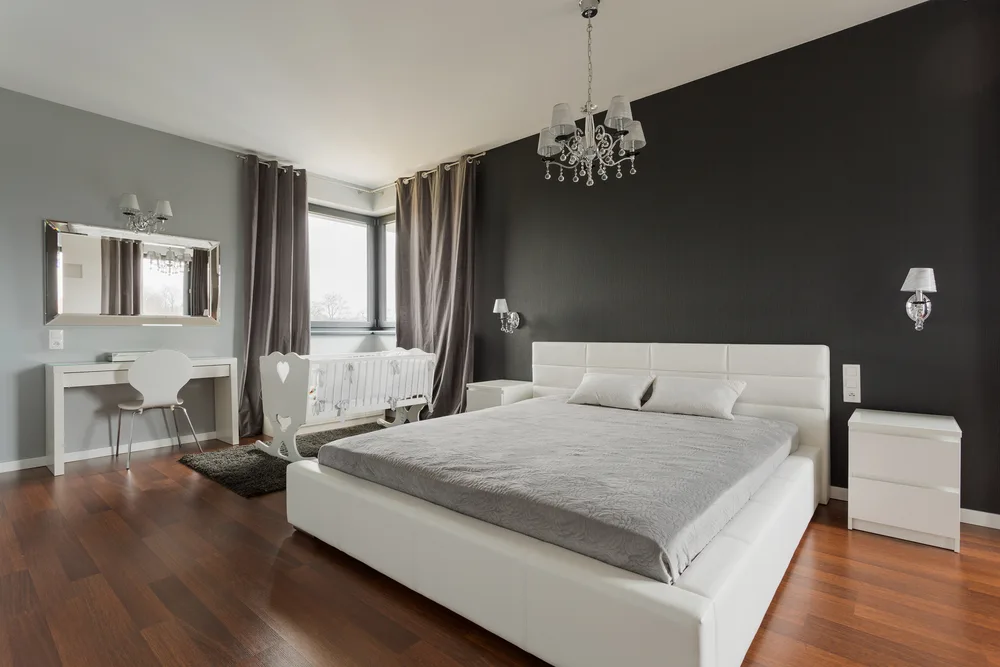 Bedroom with dark walls and floors and bright white furniture