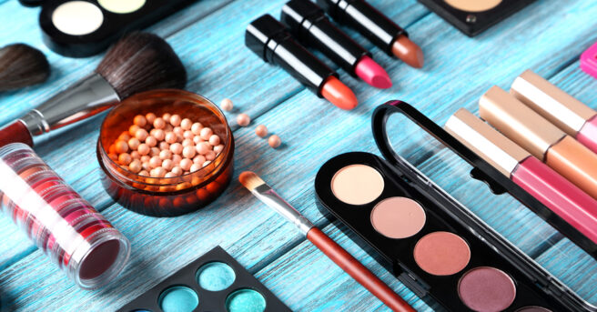 Make up brush and cosmetics on blue wooden table.