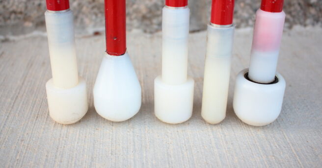 The tip of five white canes, each with a different cane tip