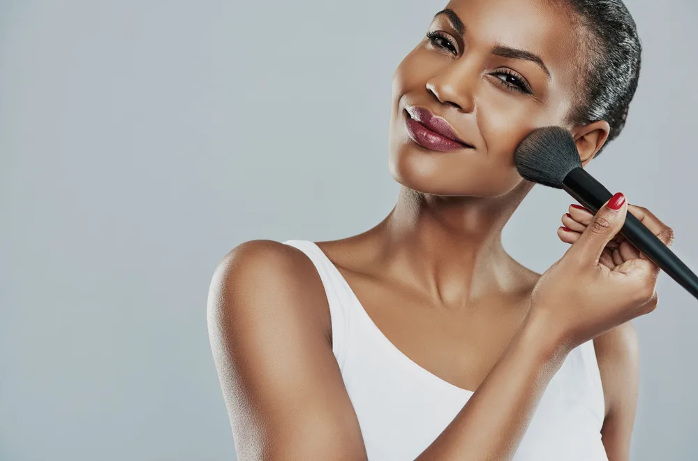 Person applying blush with a brush