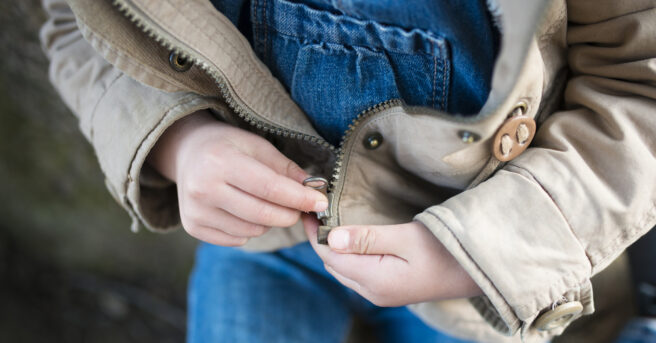 Child trying to close a zipper.