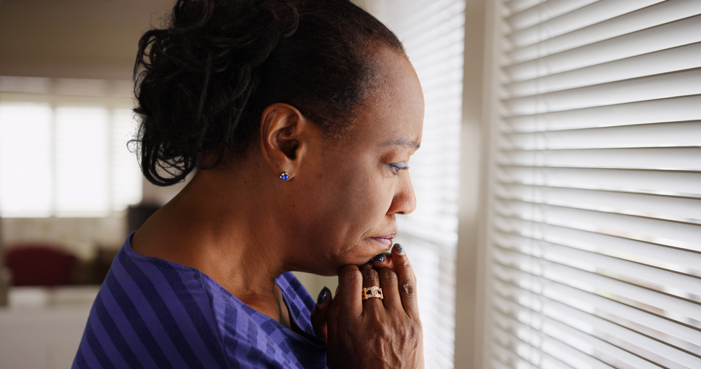 Person with hands pressed to their chin appears pensive and sad