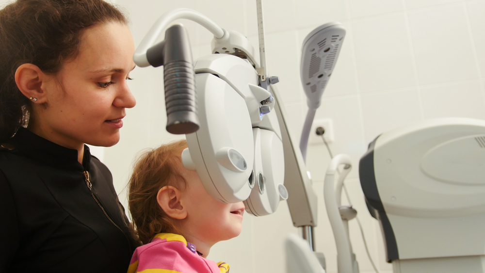 Mother and little girl - optometrist Checks Child's Eye