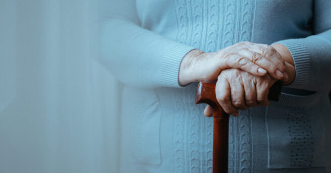 Close-up of older person holding a support cane