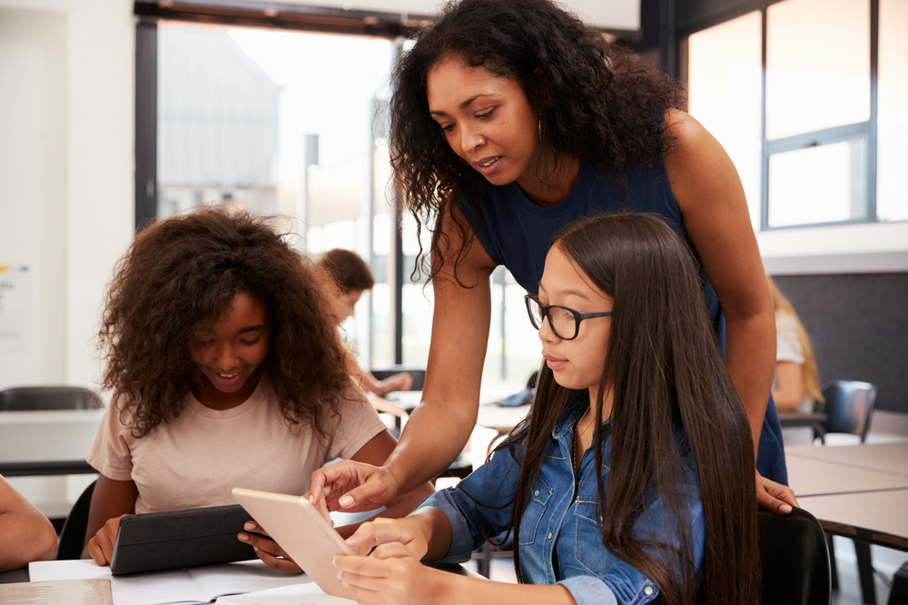 Teacher helping high school students with technology.