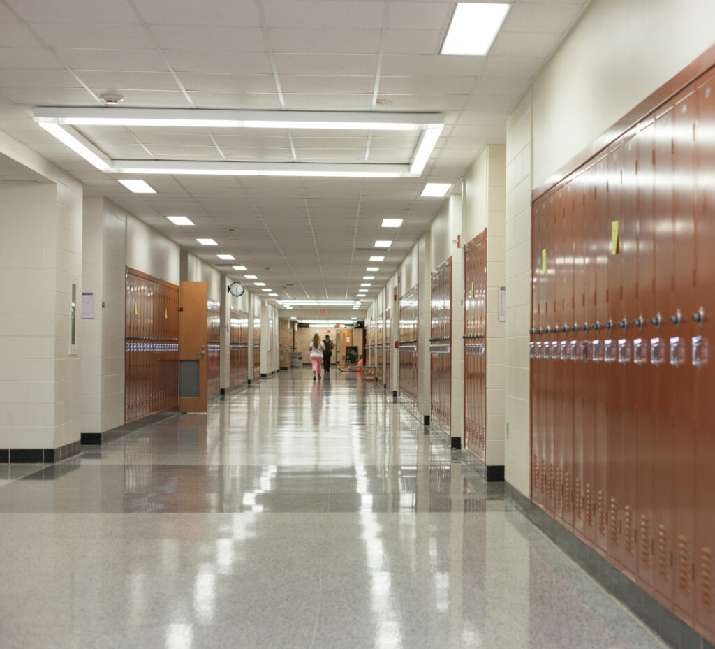 School hallway with lockers with students at the end of the hallway.