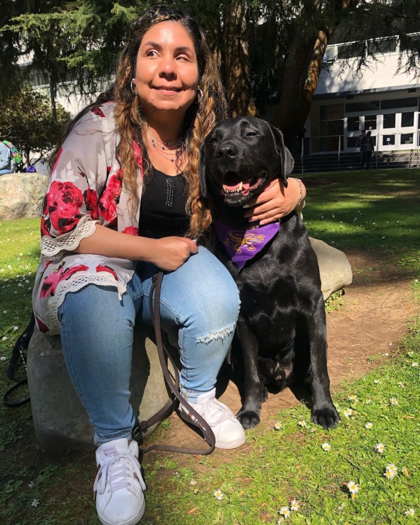 Daisy Soto with her guide dog sitting outdoors