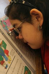 girl using magnifier to read schoolwork