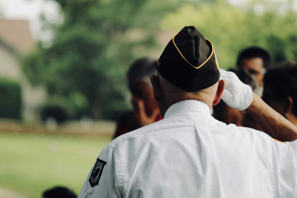A man in a military uniform, saluting, with his back to the camera,.