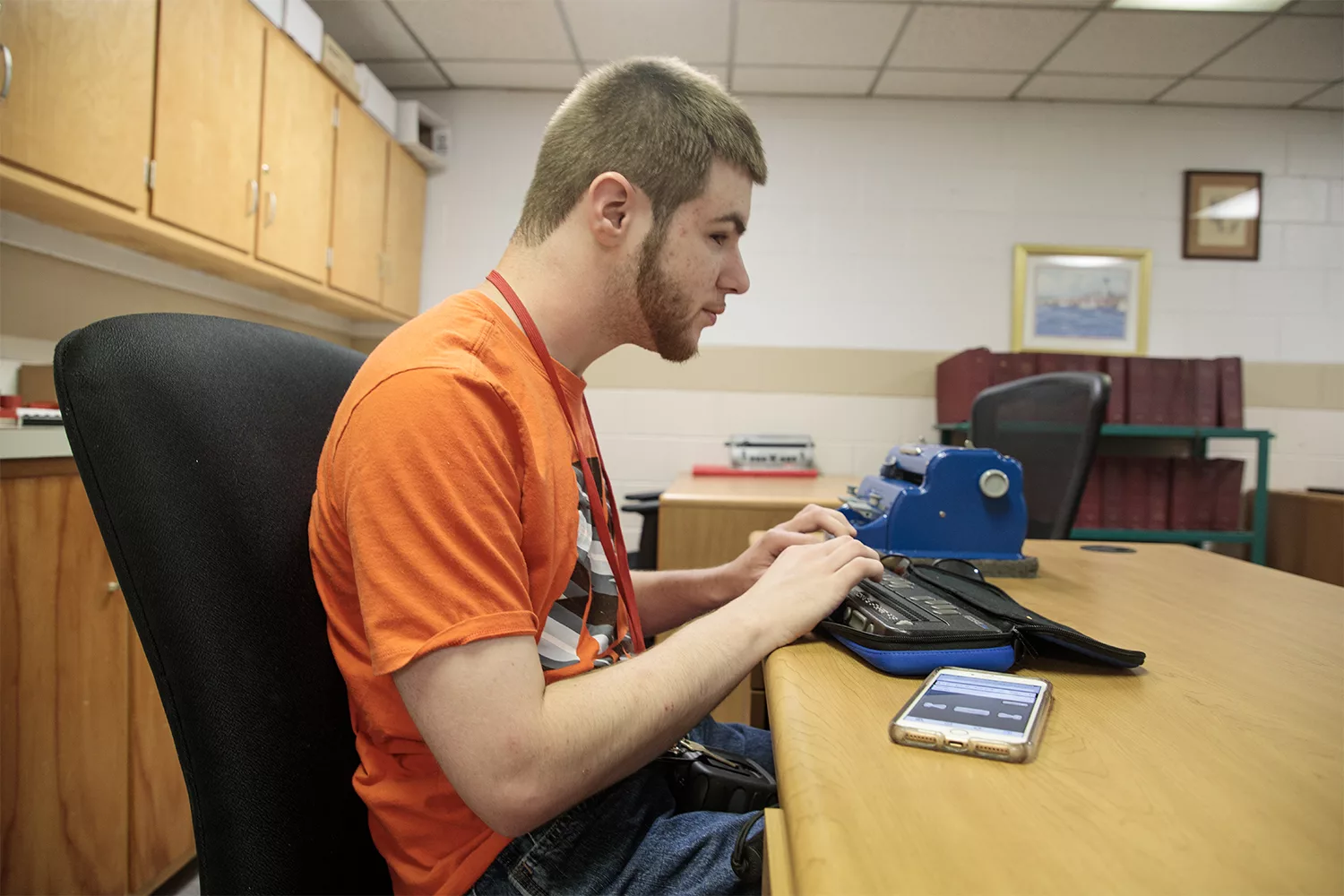 student at desk working on a refreshable braille device