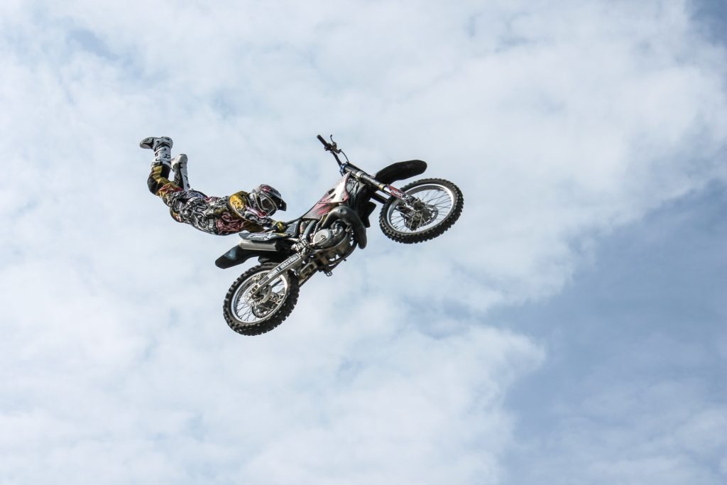 person holding onto motorcycle that is in mid air Photo by Web Donut on Unsplash