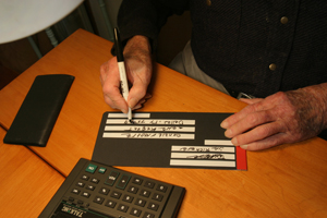 Person writing with envelope guide addressing an envelope. 